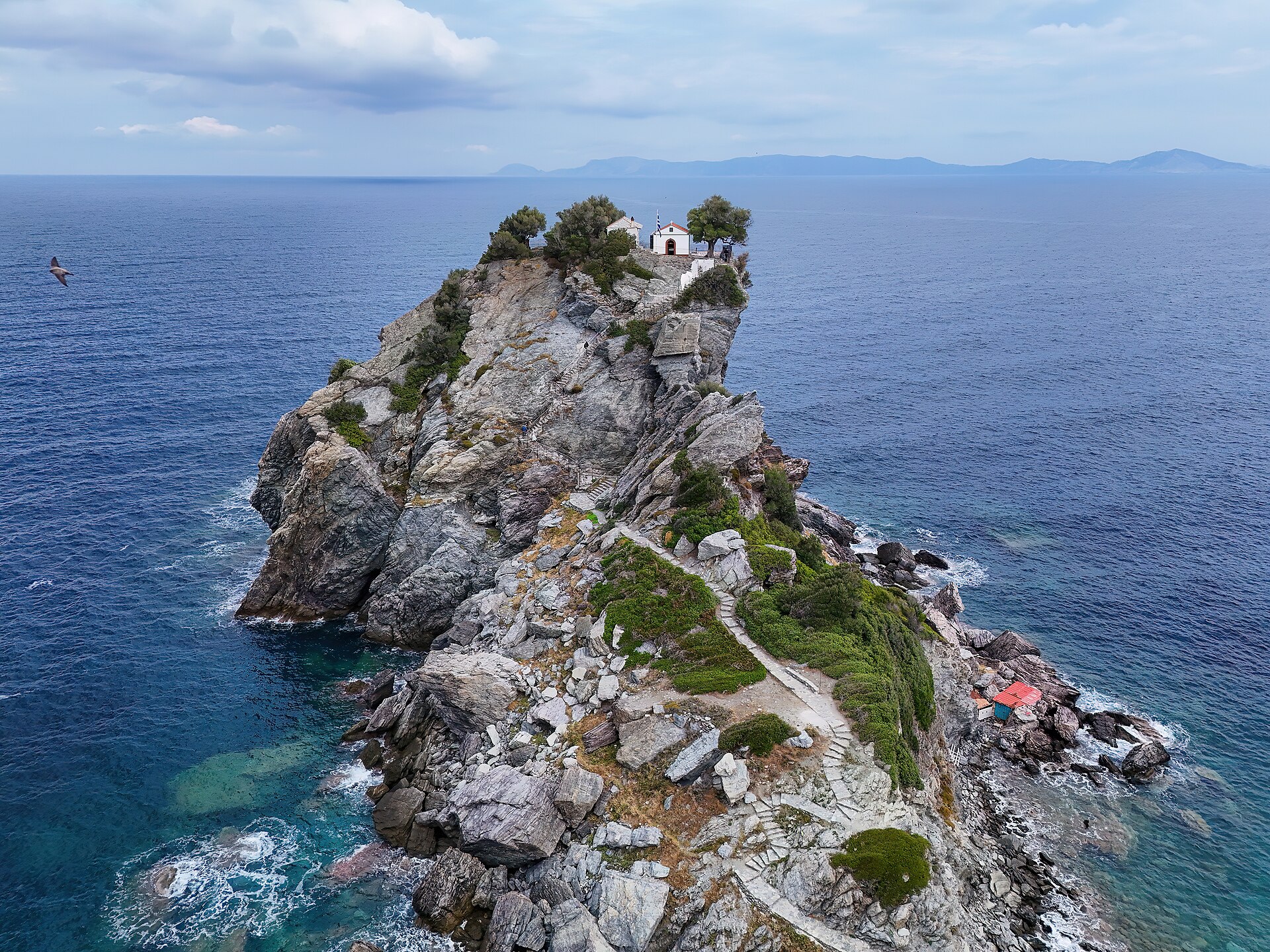 The small chapel of Agios Ioannis perched on top of a rocky outcrop above the sea on Skopelos