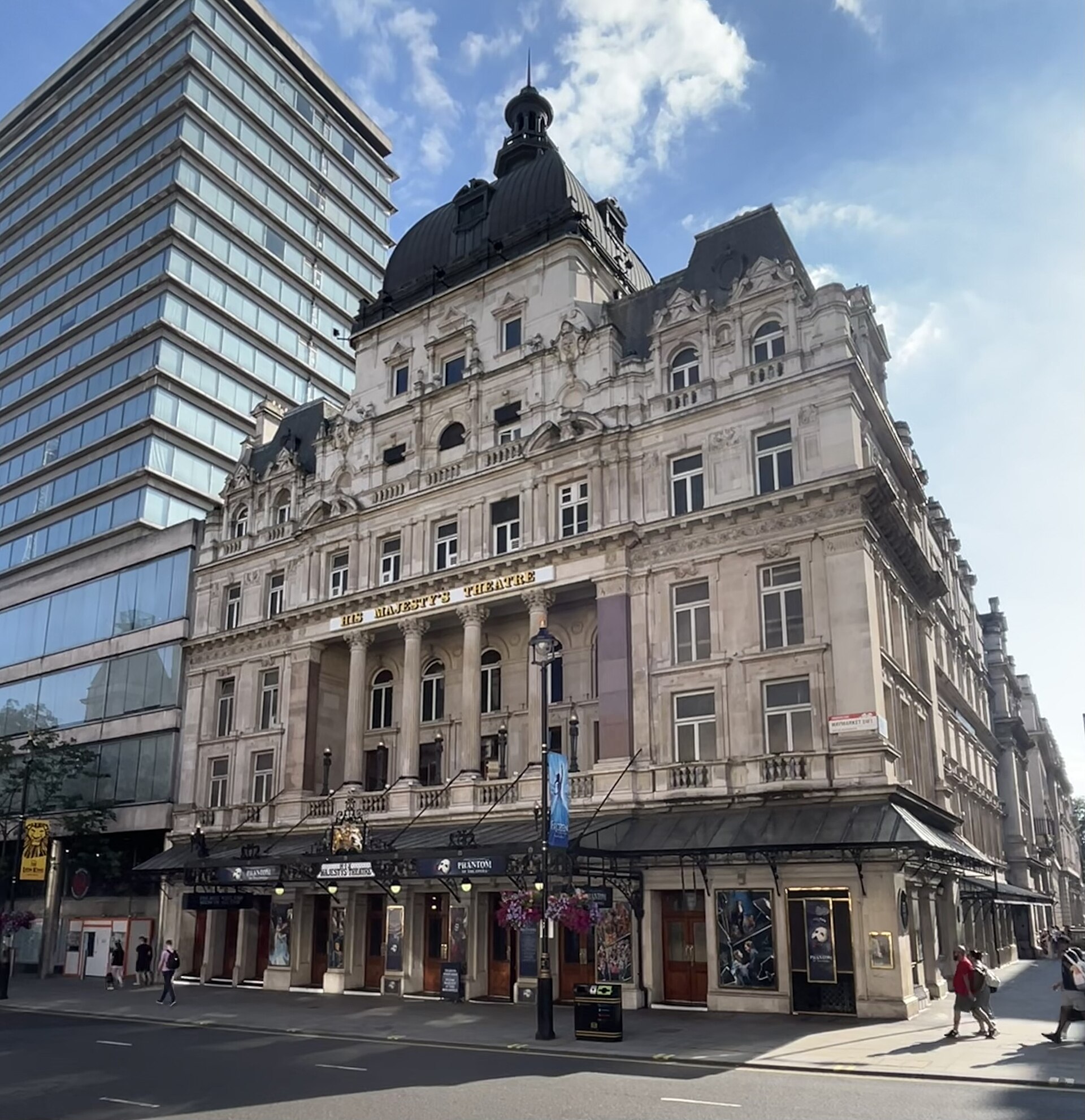 Exterior of His Majesty's Theatre on Haymarket in London, a domed Victorian building with an ornate stone facade under a blue sky