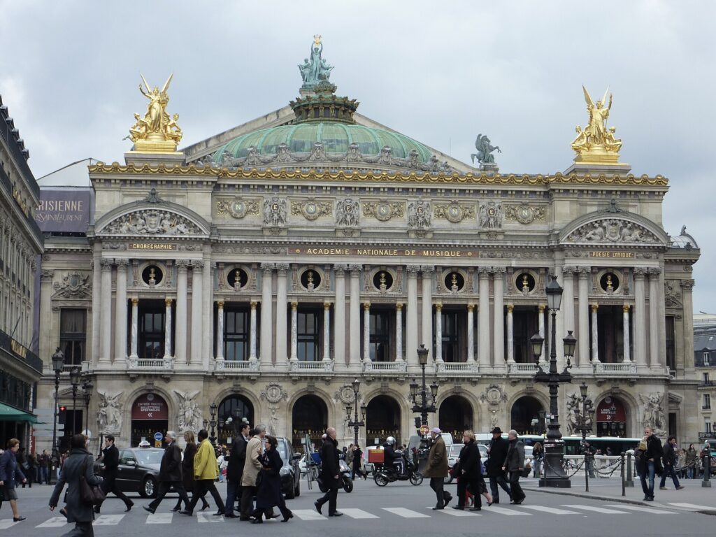 The ornate front facade of the Palais Garnier opera house in Paris with gilded statues on the roof