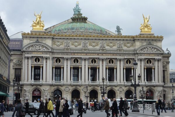 The ornate front facade of the Palais Garnier opera house in Paris with gilded statues on the roof