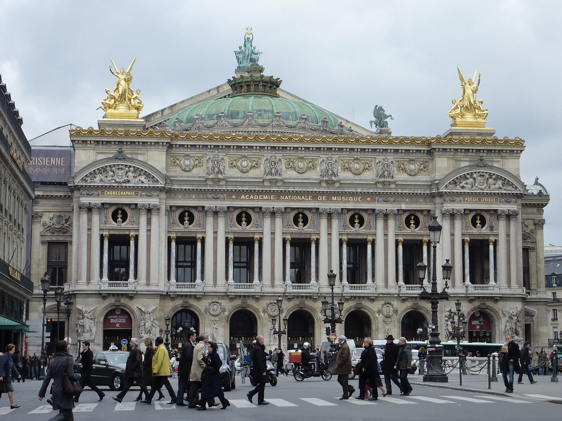 The ornate front facade of the Palais Garnier opera house in Paris with gilded statues on the roof