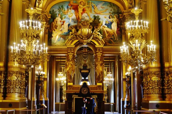 The gilded Grand Foyer of the Palais Garnier opera house in Paris, with chandeliers and a painted ceiling