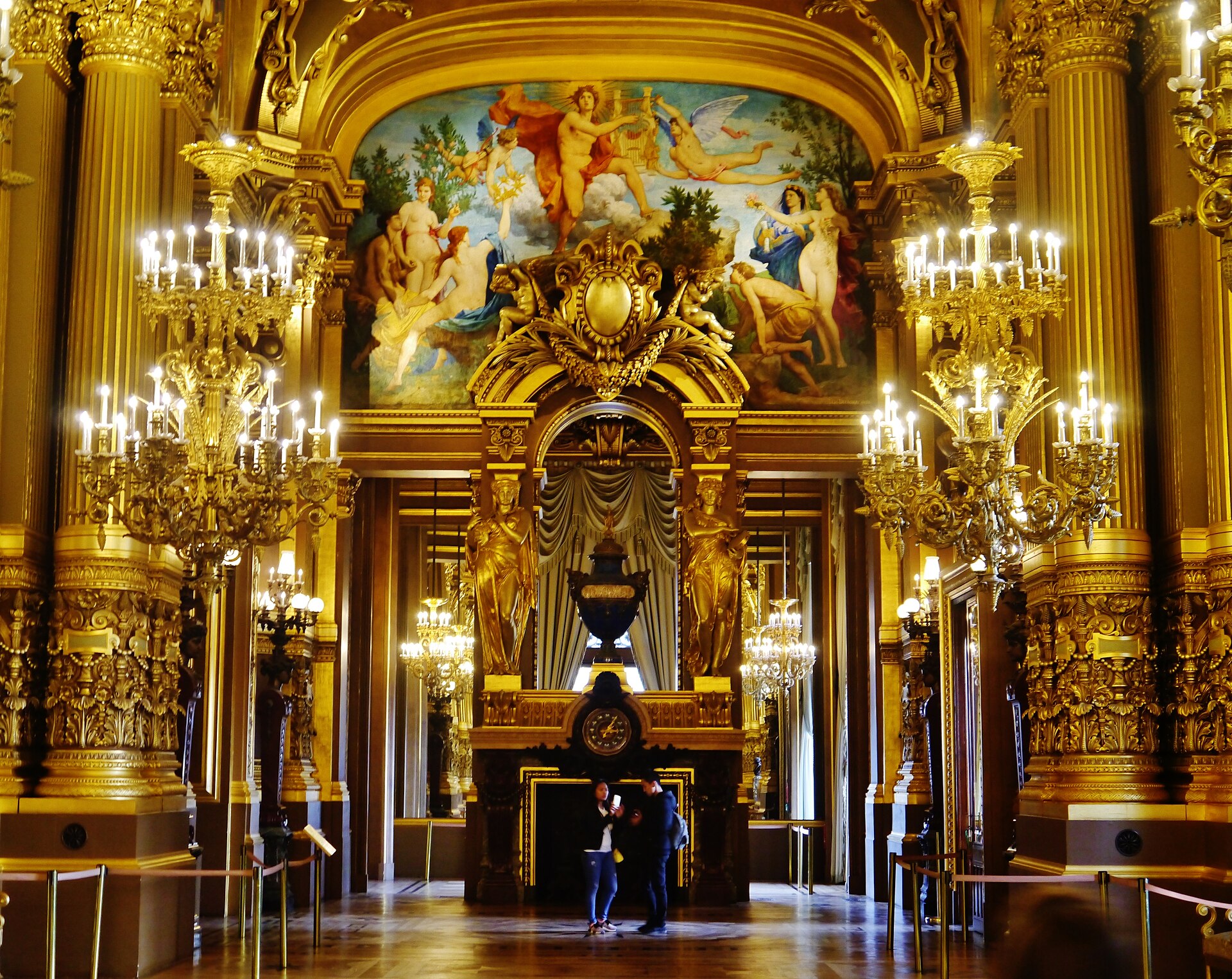 The gilded Grand Foyer of the Palais Garnier opera house in Paris, with chandeliers and a painted ceiling