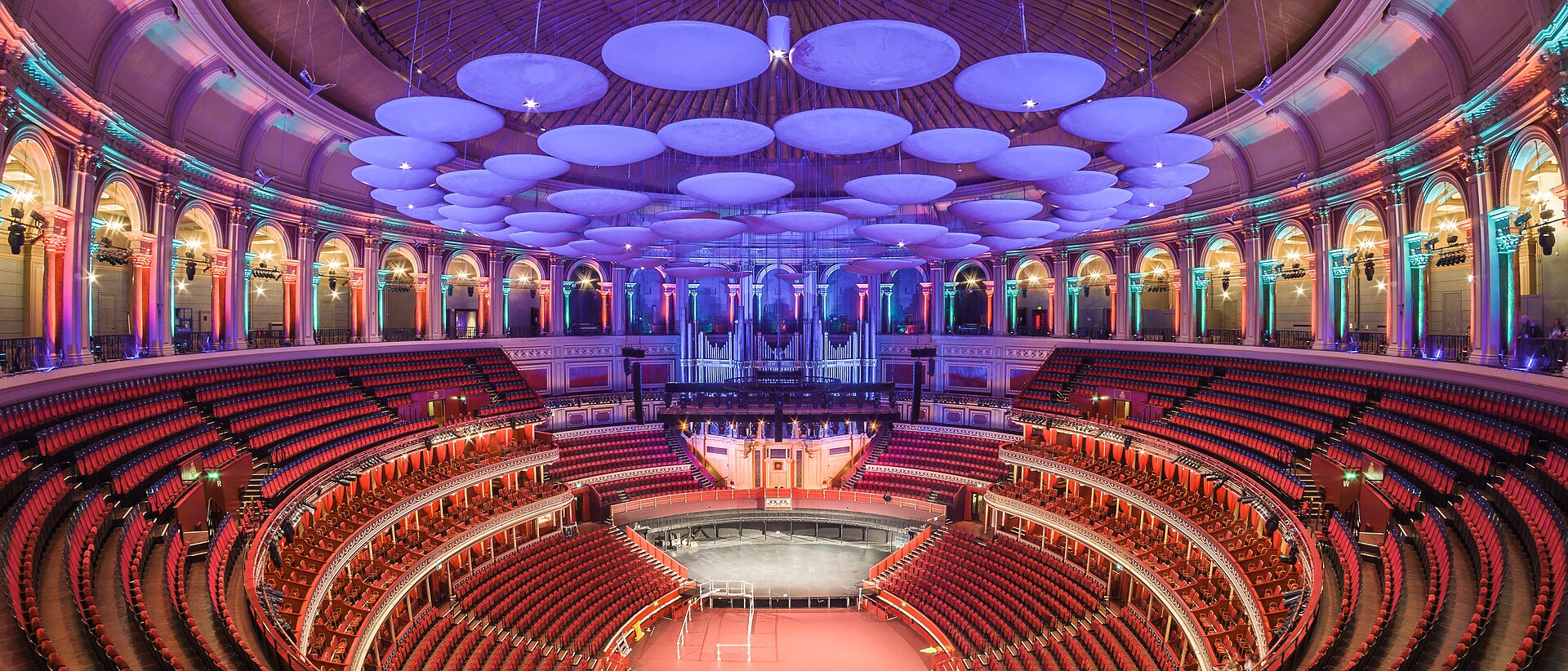 Panoramic view of the Royal Albert Hall interior from the top gallery, showing the tiers of red seating and the domed ceiling