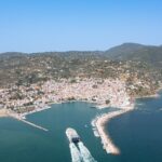 Aerial view of a ferry arriving in Skopelos harbour, with the whitewashed town on the hillside behind