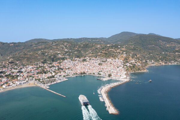 Aerial view of a ferry arriving in Skopelos harbour, with the whitewashed town on the hillside behind