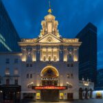 Victoria Palace Theatre in London lit up at night, with HAMILTON displayed above the entrance canopy