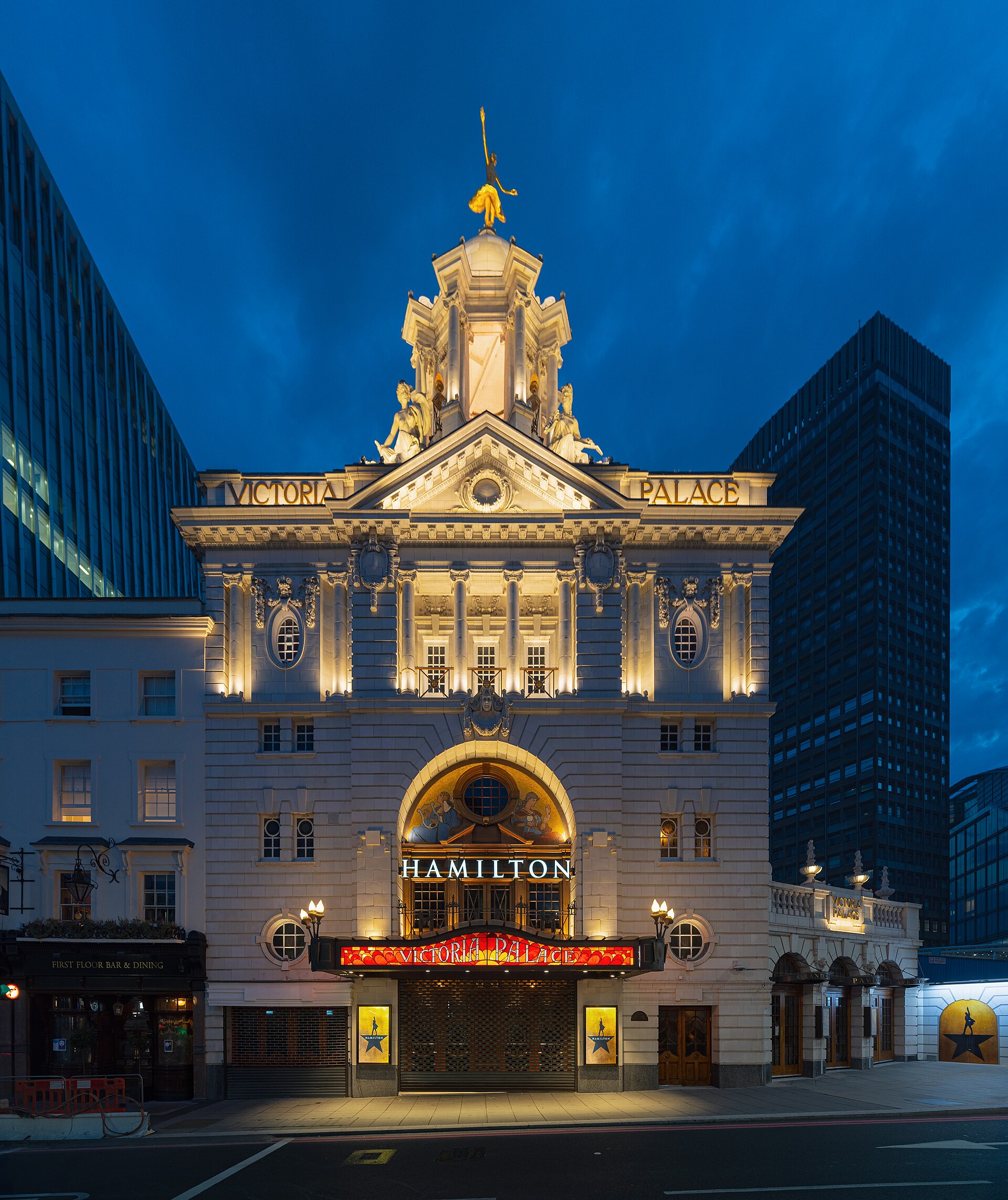 Victoria Palace Theatre in London lit up at night, with HAMILTON displayed above the entrance canopy